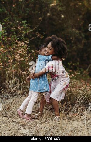 Portrait of two sisters hugging in backlit field Stock Photo