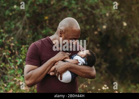 Close up happy father holding and smiling at newborn baby outside Stock Photo