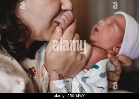 Close up detail of mother in hospital kissing newborn son hand Stock Photo