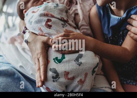 Close up detail of mother holding newborn son with sibling Stock Photo