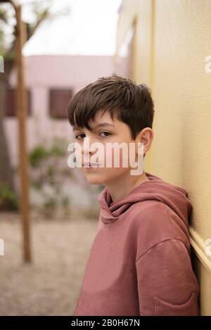 Portrait of a teenage boy leaning against wall looking camera Stock Photo