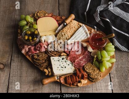 Close up of charcuterie board of meat, cheese, crackers on wood table. Stock Photo