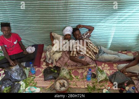 02.11.2019, Adama, Oromiyaa, Ethiopia - A woman and two men are sitting on the floor chewing khat. 8000 IDPs from the Somalia region live in four refu Stock Photo