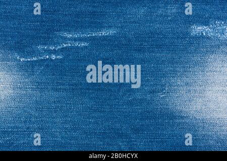 Jeans torn denim texture. Material, background. Light blue denim jeans fragment. Vintage jeans torn denim texture. Stock Photo