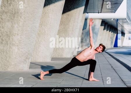 Utthita Parsvakonasana is a complicated yoga posture that stretches the trunk muscles, practiced by a man. Stock Photo