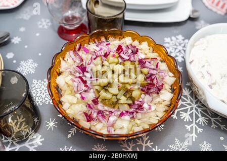 Raw herring in oil with onion and cucumber, standing in a bowl on the Christmas table in Poland. Stock Photo