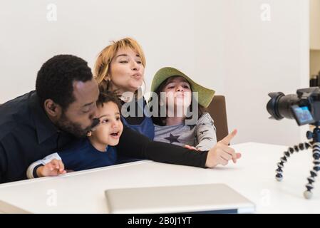 multiethnic family, black father and white mother with two mixed-race children, send kisses to their relatives in a video call, family of multi-racial Stock Photo