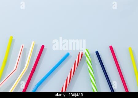 Colorful plastic drinking straws on a blue glass. The concept of Plastic flooding the world. space for text Stock Photo