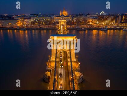 Budapest, Hungary - Aerial view of the beautiful illuminated Szechenyi Chain Bridge over River Danube at blue hour with St. Stephen's Basilica and hea Stock Photo