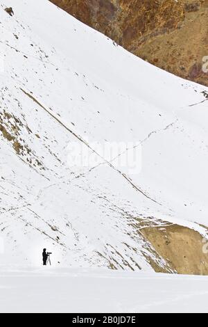 Photographer searching snow leopard in Rumbak, valley. Hemis national park, Himalayas, Ladakh, India Stock Photo