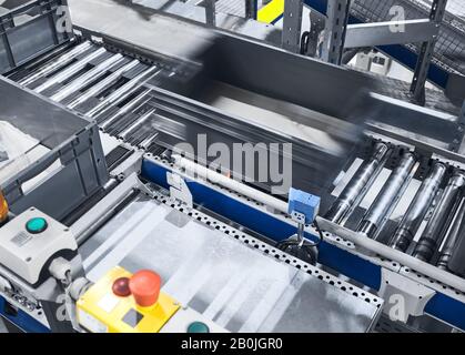 Modern conveyor system with box in motion, shallow depth of field. Stock Photo