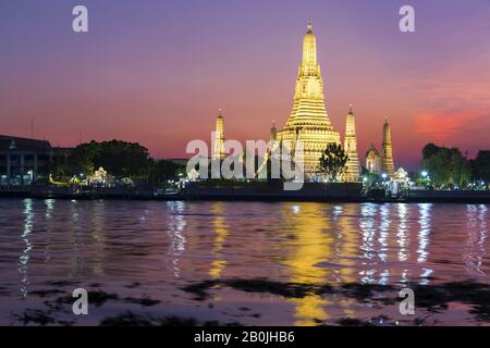 Dramatic Sunset Sky Colors over Wat Arun Temple of Dawn Buddhist Monument Reflected in Chao Phraya River in City of Bangkok, Thailand Southeast Asia Stock Photo