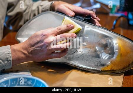A man changes a burned out headlamp and sands down the outer lens to make it shine brighter at night Stock Photo
