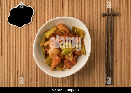 bowl of sweet and sour chicken and an empty chalkboard on a table Stock Photo