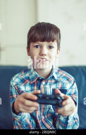 Little excited kid playing video game, holding controller Stock Photo