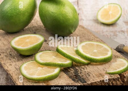 whole and sliced limes on a wooden cutting board Stock Photo
