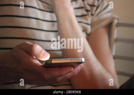Closeup on a man's hands as he is using a smartphone Stock Photo