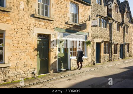 A well-dressed woman walks past a village jewellers shop in Lacock Wiltshire England UK Stock Photo