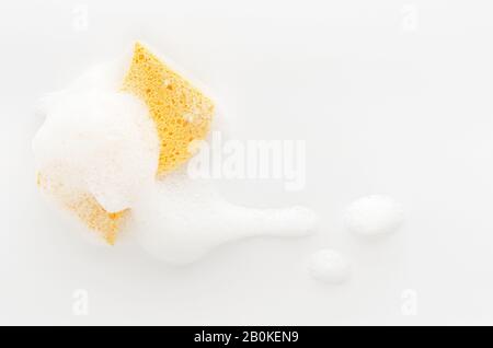 Yellow soapy sponge with foam on white background. Cleaning concept. Copy space Stock Photo
