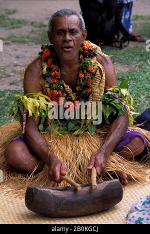 FIJI, VITI LEVU ISLAND, VISEISEI VILLAGE, MAN IN TRADITIONAL COSTUME WITH SLIT-DRUM Stock Photo