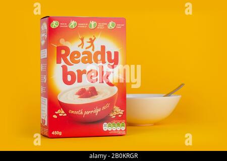 A box of Ready Brek cereal shot on a yellow background along with a breakfast bowl and spoon. Stock Photo