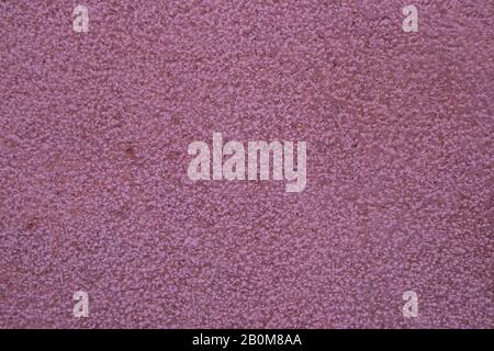 Pinkish background shows a wall decorated with grains of different sizes that produce random roughness Stock Photo