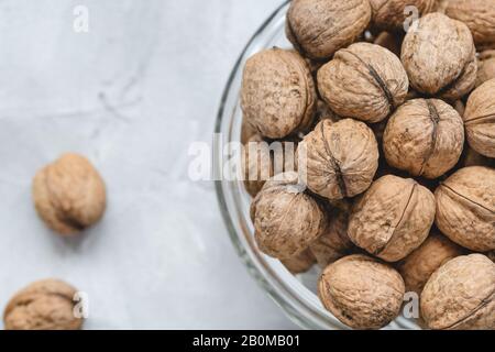 Uncracked walnuts in shell in bowl on gray background, concept of healthy eating vegan food. Close up, selective focus, copy space. Stock Photo