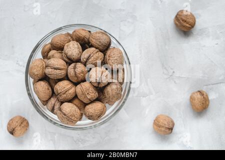 Uncracked walnuts in shell in bowl on gray background, concept of healthy eating vegan food. Close up, selective focus, copy space. Stock Photo
