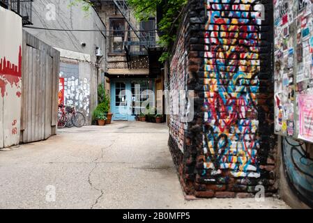 A mural of hearts are spray painted on a brick wall in an alley leading to Freemans Restaurant on the Lower East side of New York City.