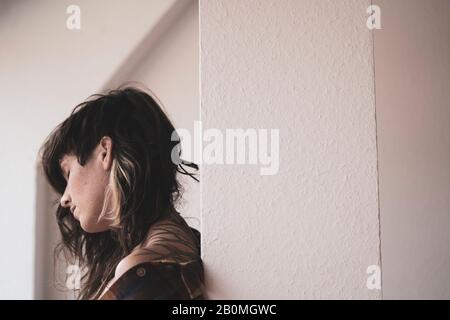 natural woman with curly hair has peaceful moment in window light Stock Photo