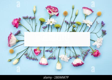 Frame made of fresh  flowers on table. Copy space on blank empty white paper Stock Photo