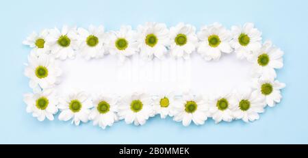 On a blue background is a rectangular frame of flowers. Postcard, greetings card. Stock Photo