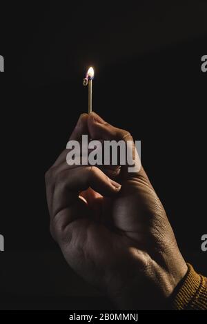 The hand of an adult man holding a burning match Stock Photo