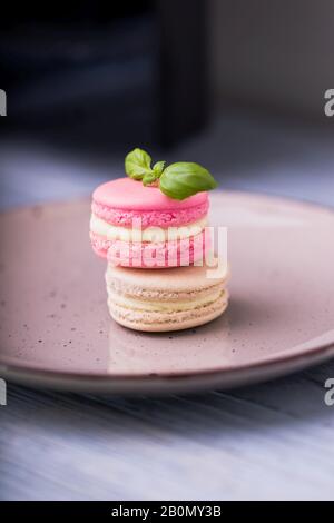 Pink raspberry and beige vanilla macaroons on a ceramic plate Stock Photo
