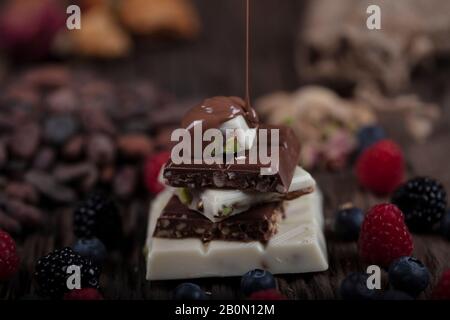 Christmas Chocolates. Bars of chocolate with forest berries fruit and  over festive background. An assortment of white, dark, and milk chocolate with Stock Photo