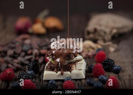 Christmas Chocolates. Bars of chocolate with forest berries fruit and  over festive background. An assortment of white, dark, and milk chocolate with Stock Photo