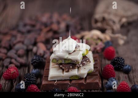 Christmas Chocolates. Bars of chocolate with forest berries fruit and  over festive background. An assortment of white, dark, and milk chocolate with Stock Photo