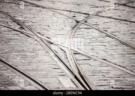 Close up on a tramway rail switch on a cobblestone pavement on an old and obsolete street where public transportation in ensure by tram trains.  Pictu Stock Photo