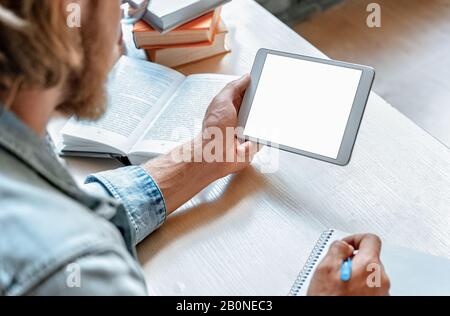 Student hold modern digital tablet make notes in notebook empty mock up screen Stock Photo