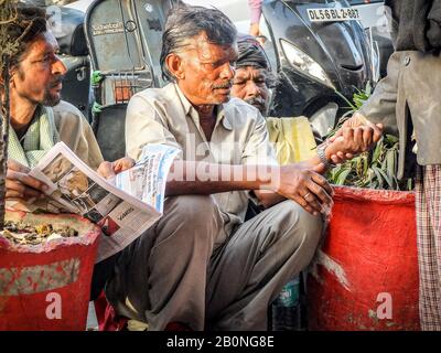 A man has his pulse taken by a friend whilst sitting outside Gurudwara sis ganj sahib ji Sikh temple, New Delhi,2018. Stock Photo