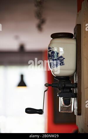 Close up of an old manual coffee bean grinder hanging on the wall Stock Photo