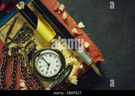 Vintage pocket watch and brass pen on old book. At 8 o’clock in morning. Top view and copy space. Education and vintage style concept. Stock Photo