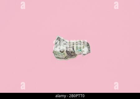 crumpled up dollar bill  on pink background Stock Photo