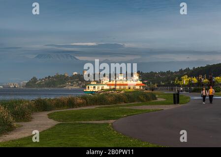 Mt Rainier Hovers Over Downtown Tacoma and Commencement Bay as Seen from Point Ruston with people walking and Riding Bikes Stock Photo