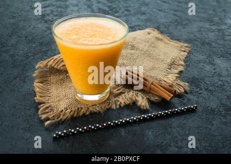 Citrus smoothie with cinnamon sticks on a black background. Close-up. Stock Photo