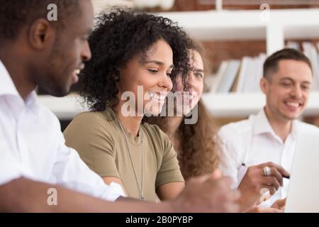Happy diverse employees team working on project together, smiling African American woman discussing work with colleagues, coworkers having fun, pleasa Stock Photo