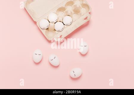 Festive Easter pink background with white eggs and eyes drawn on them. The inscription is a happy Easter. Stock Photo