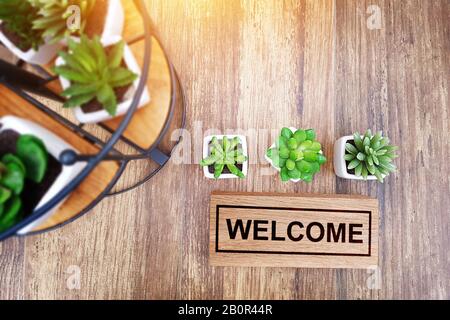 warm welcome sign for business concept. wooden welcome sign on table decorate with little cactus and copy space for your text, top view Stock Photo