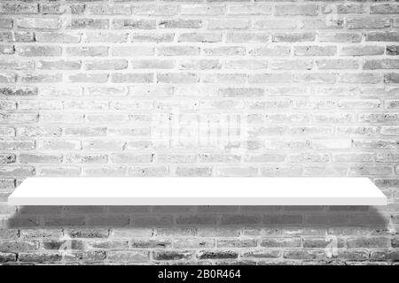 empty white shop shelf with shadow , retail shelf on brick vintage wall room background. white shelf isolated on brick background. shelf mockup Stock Photo
