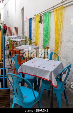 Polignano a Mare, Italy - September 17, 2019: Colorful arrangement of the cafe in one of the side streets of Polignano a Mare. Italy Stock Photo